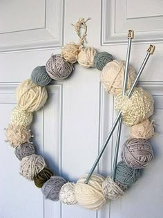 a yarn wreath with knitting needles and balls of yarn hanging on the front door,