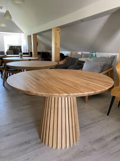 a wooden table sitting in the middle of a room with chairs and tables around it