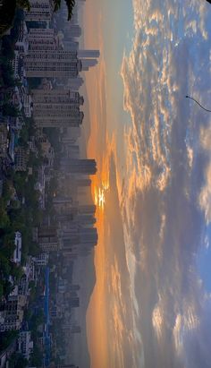 the sun is setting behind some clouds and buildings