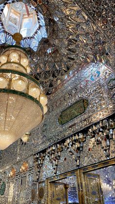 a chandelier hanging from the ceiling in a room with mosaic tiles and mirrors