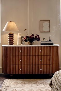 a room with a dresser, lamp and pictures on the wall