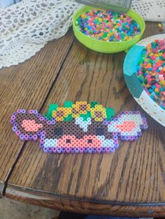 a table topped with lots of colorful beads next to a bowl of sprinkles