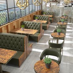 an empty restaurant with wooden tables and green leather seats, plants in pots on the table