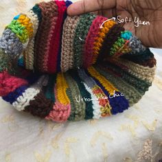 there is a hand holding a multicolored crocheted headband