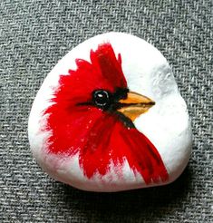 a painted rock with a red and white bird sitting on it's back end