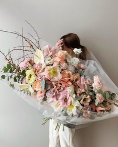 a woman holding a bouquet of flowers in front of her face and covering her face