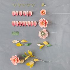 flowers and hair pins arranged on a gray surface with yellow, pink, and green leaves