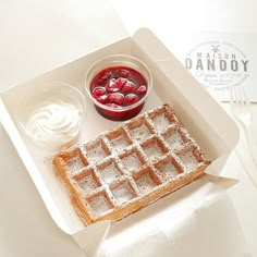 a waffle with powdered sugar and fruit in a bowl next to a cup of yogurt