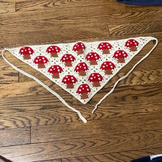 a triangle with red mushrooms on it sitting on top of a wooden floor next to a pair of scissors