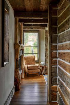 an open door leading to a living room with wood floors and logs on the walls