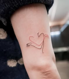 a woman's arm with a small heart tattoo on the left side of her arm