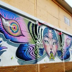 a wall that has been painted with different colors and designs on it, including an image of a woman's face