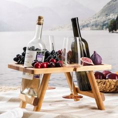 two wine bottles and three glasses on a table with fruit in front of the water