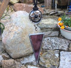 a purple glass sun catcher sitting on top of a rock next to a potted plant