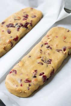 two pieces of bread sitting on top of white parchment paper next to each other, with cranberry toppings