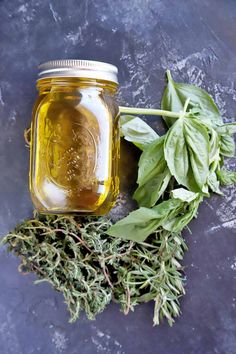 a jar filled with liquid next to some herbs