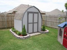 a backyard with a small shed and a red fire hydrant in the grass next to it