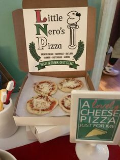 small pizzas sitting in a box on top of a table next to a sign