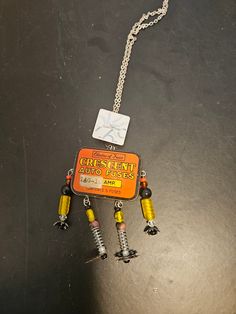 an orange and yellow necklace with screws attached to it on a black table top