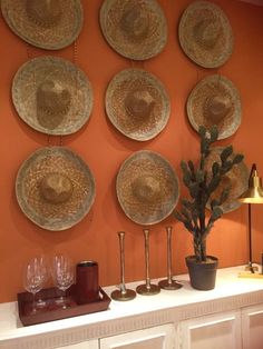 plates are hanging on the wall above a table with wine glasses and a potted plant