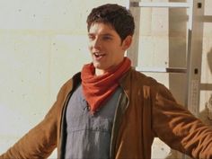 a young man standing in front of a white wall