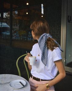 a woman sitting at a table with a cup in her hand