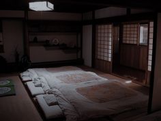 an empty bed in a room with wooden floors and windows on either side of it