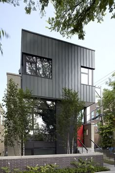 a black house with trees and bushes around it