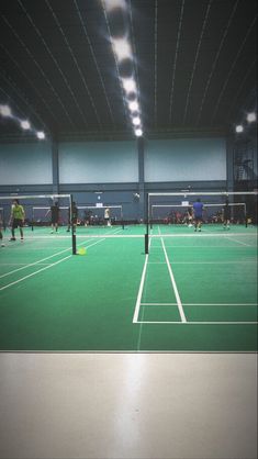 an indoor tennis court with people playing on it