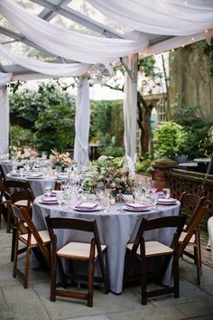 an outdoor dining area with white draping and tables set up for a formal dinner