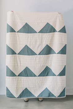 a white and blue quilt is hanging on a wall