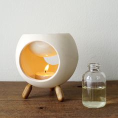 a white vase sitting on top of a wooden table next to a bottle filled with liquid