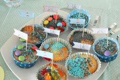 some cupcakes are on a plate with little flags and candy in the middle