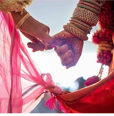 two people holding hands with bracelets and jewelry on their wrists, while one holds the other's hand