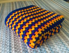 a multicolored crocheted blanket on top of a bed