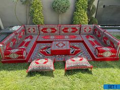 a large red couch sitting on top of a lush green grass covered field next to a wall