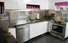 a kitchen with stainless steel counter tops and white cabinets, including a dishwasher