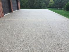 an empty driveway in front of a brick building with two garage doors on each side