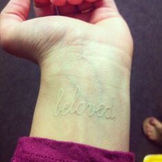 a woman's wrist with the word believe written on it, in cursive writing