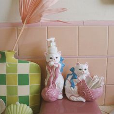 two figurines sitting on top of a table next to a vase and fan