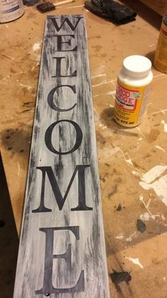 a wooden sign that says welcome to me on the table next to some paint bottles