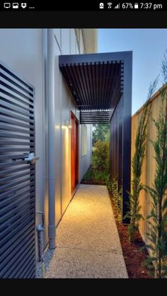 an outdoor walkway leading to a building with lights on the side and trees in the background