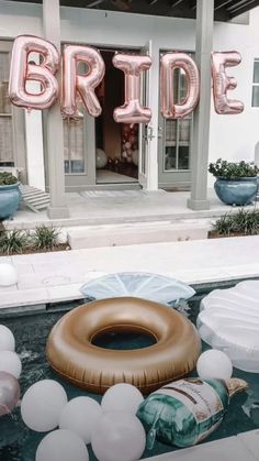 an inflatable donut floating on top of a pool surrounded by balloons and flowers