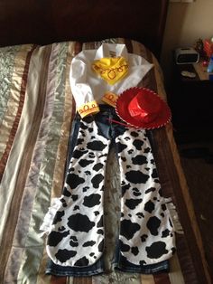 a pair of cow print jeans laying on top of a bed next to a red hat