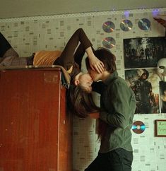 two people standing next to each other near a dresser