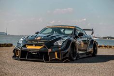 a black sports car parked in front of the ocean