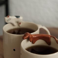 two mugs with hot chocolate in them sitting on a table