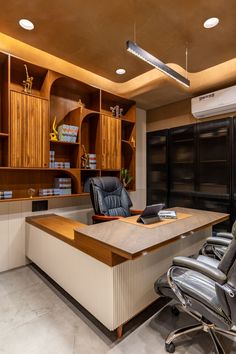 an office with wooden cabinets and black leather chairs in front of a desk that has a laptop on it