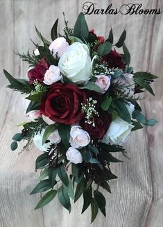 a bridal bouquet with roses and greenery on a wooden background that says dardas blooms