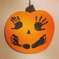 an orange pumpkin with handprints on it hanging from a hook in a wall